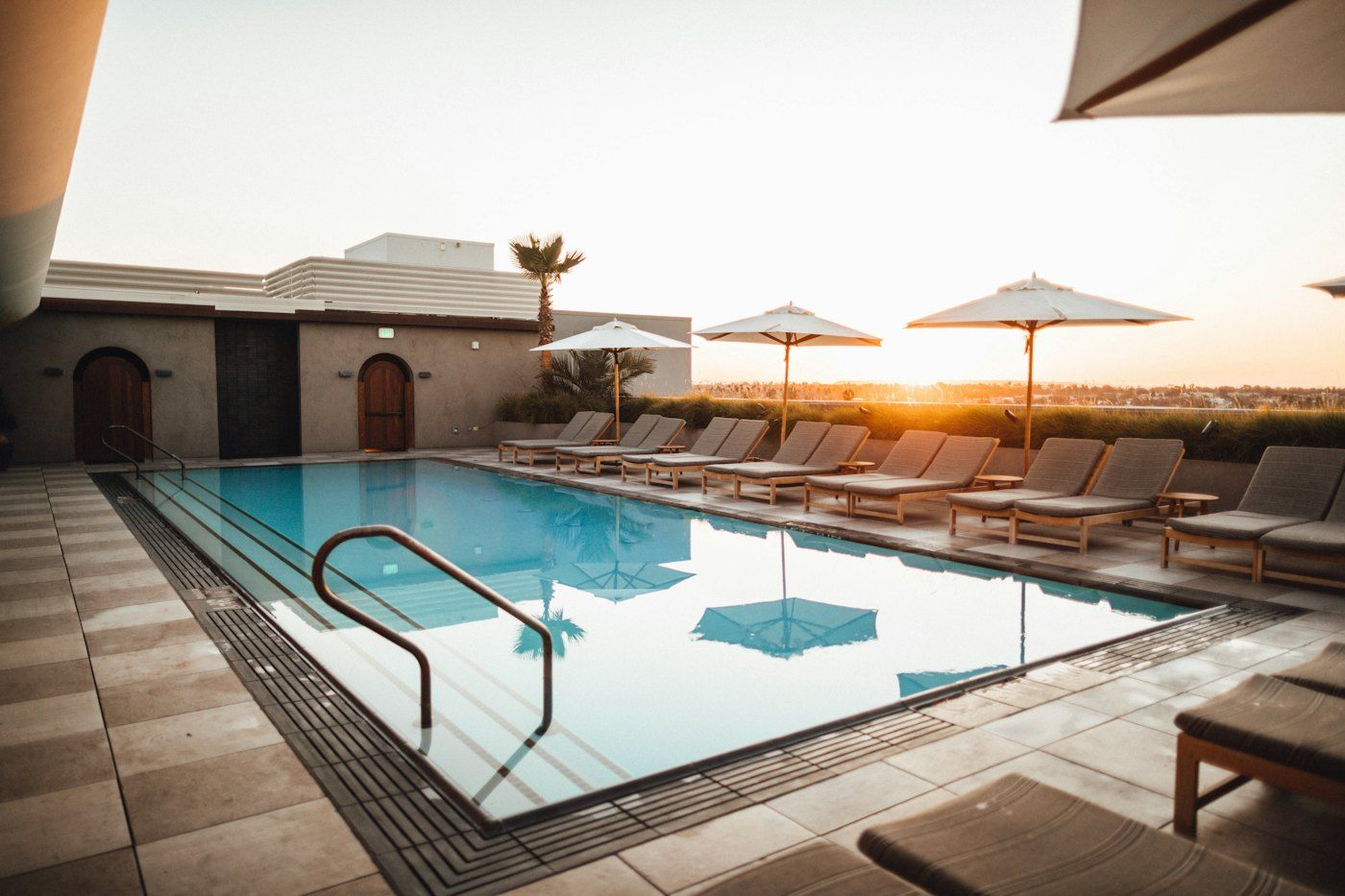 Resort-style pool deck with lounge chairs at sunset